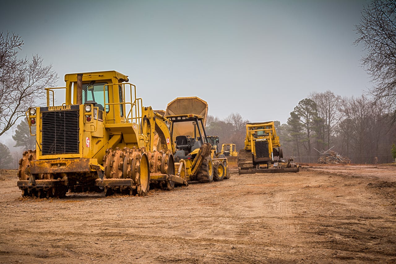 Yellow construction vehicles at a worksite in Raleigh, NC on a cloudy day.